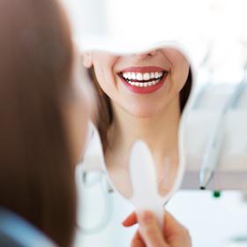 Woman looking at her smile in a mirror