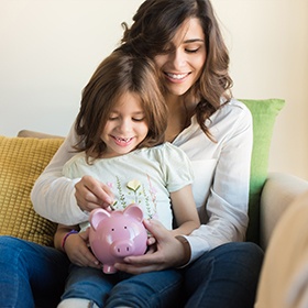 Mother and daughter putting coins in piggy bank