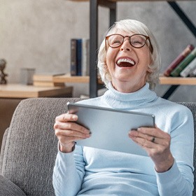 Senior woman holding a tablet and laughing