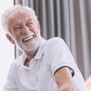 Senior man in white shirt sitting on couch and smiling