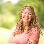 Woman in pink shirt smiling outside