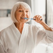 woman brushing teeth in bathroom mirror 