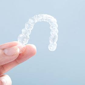 a person in Goode holding SureSmile clear aligners