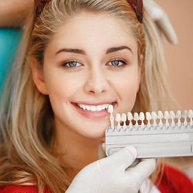 Woman's smile compared with tooth color chart