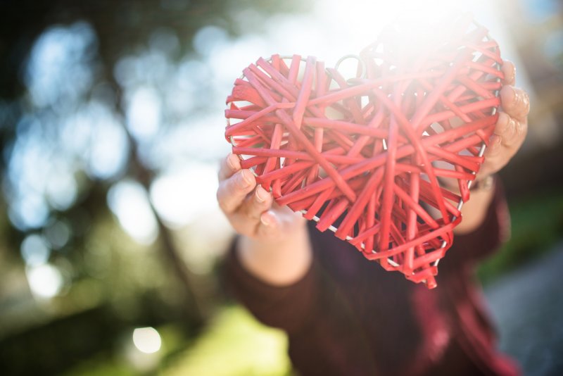 A person holding a heart made from string.