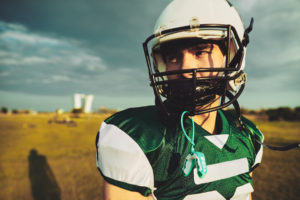 Young football player wearing a helmet with custom mouthguard