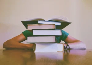 Student behind stack of books on desk