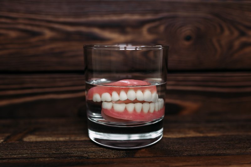 a pair of dentures soaking in a glass of water