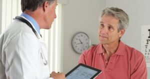 Dentist consulting with older man.